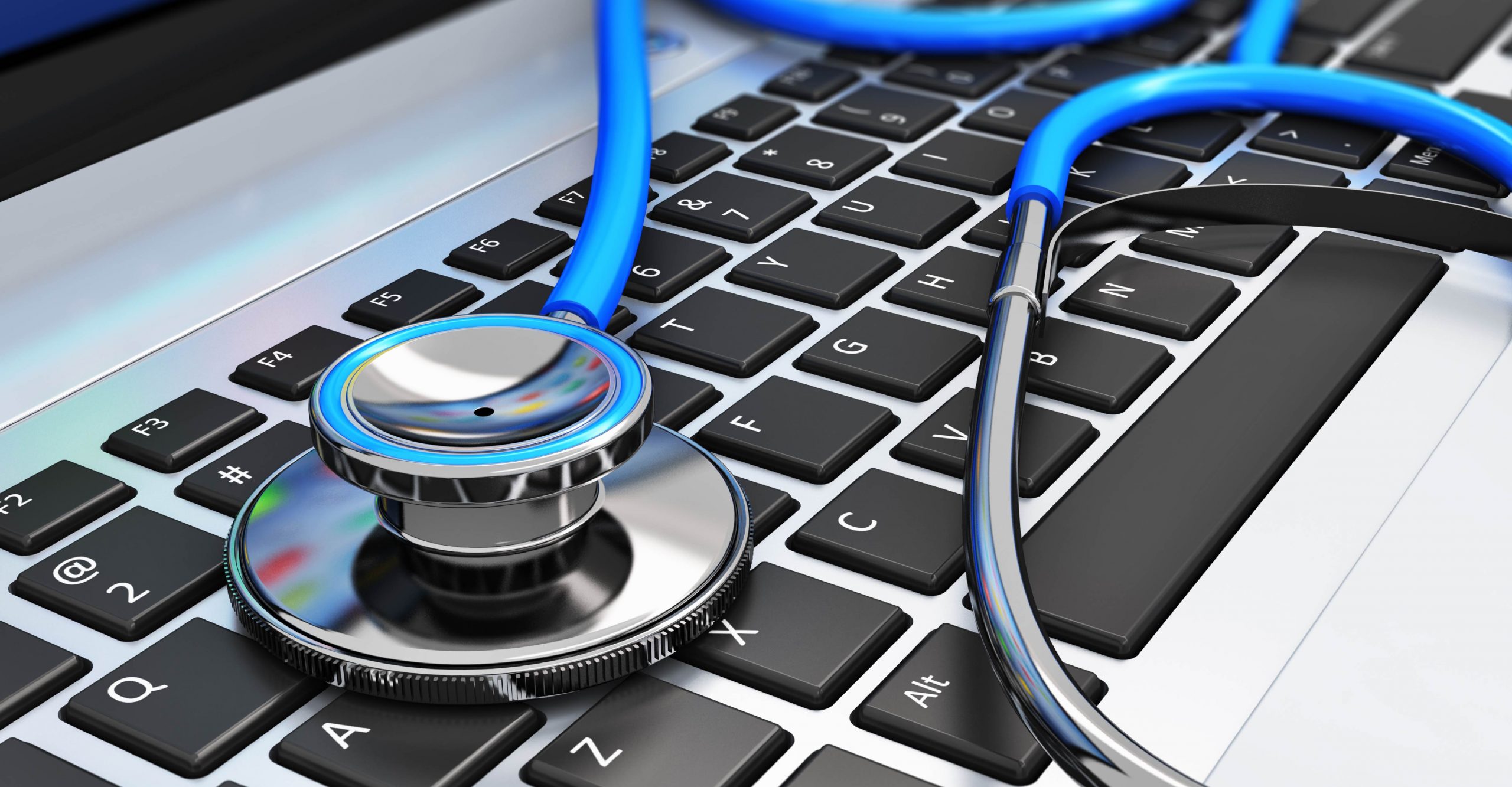 A stethoscope lies on the keyboard of a laptop, symbolizing the intersection of healthcare and technology.