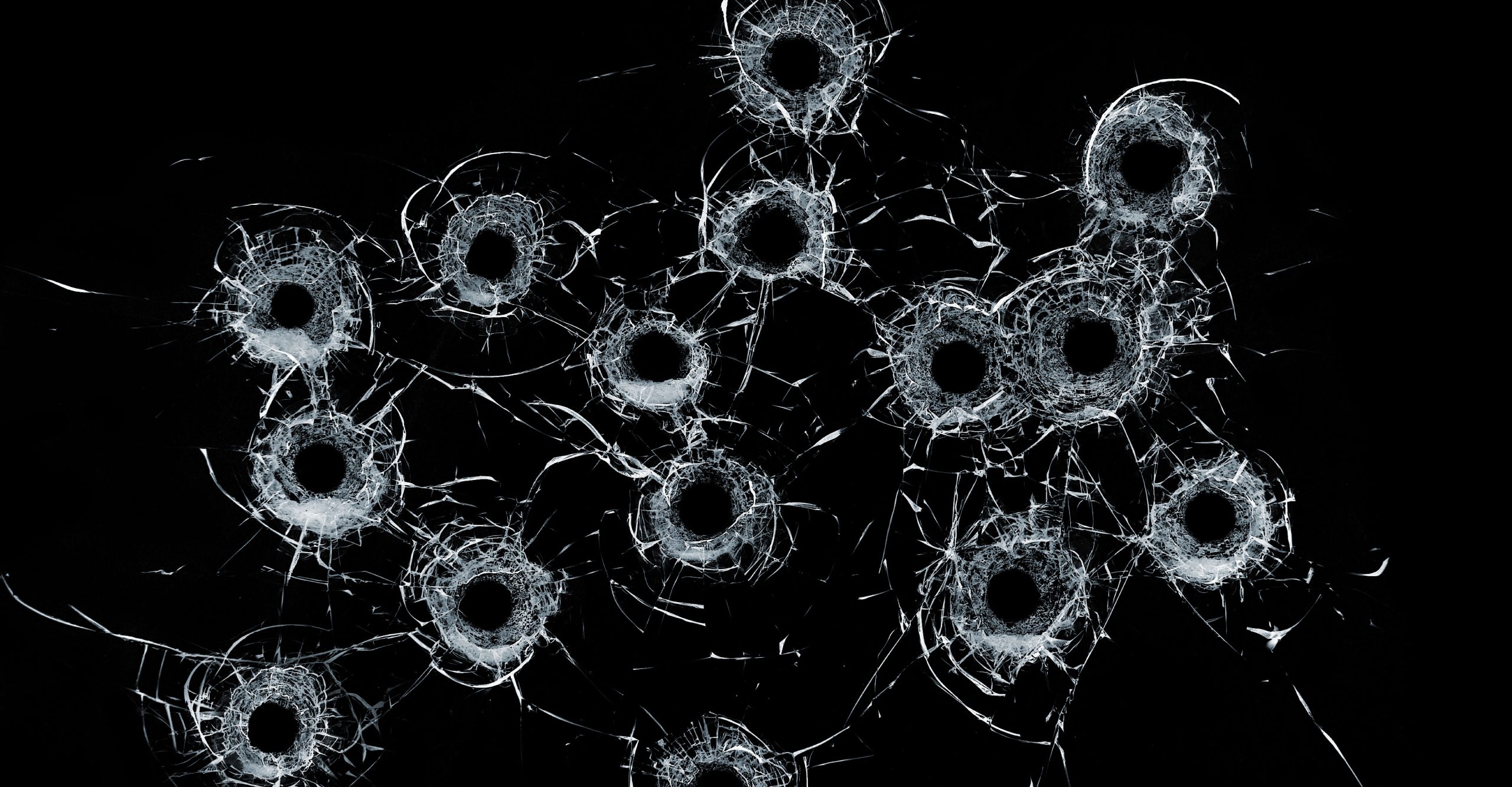 A black background with multiple visible bullet holes and cracks spreading outward from the points of impact, symbolizing the challenges faced in workplace productivity with technology.