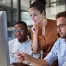 a group of young tech entrepreneurs group around a monitor to solve business problems together